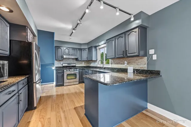 a kitchen with stainless steel appliances granite countertop a refrigerator a stove and a sink