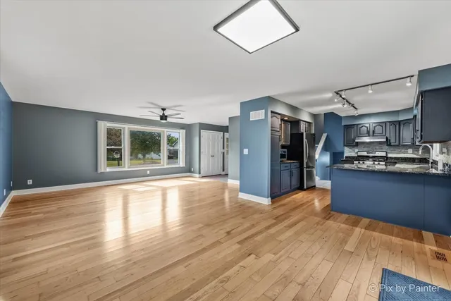 a view of a kitchen with stainless steel appliances wooden floor and large windows
