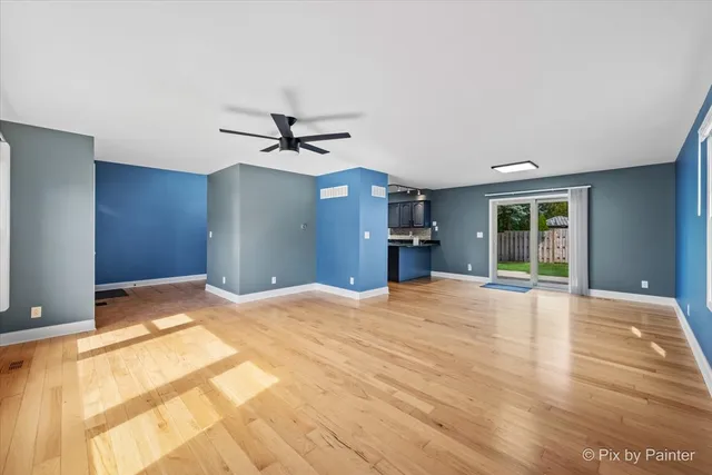 a view of an empty room with a chandelier fan and a window