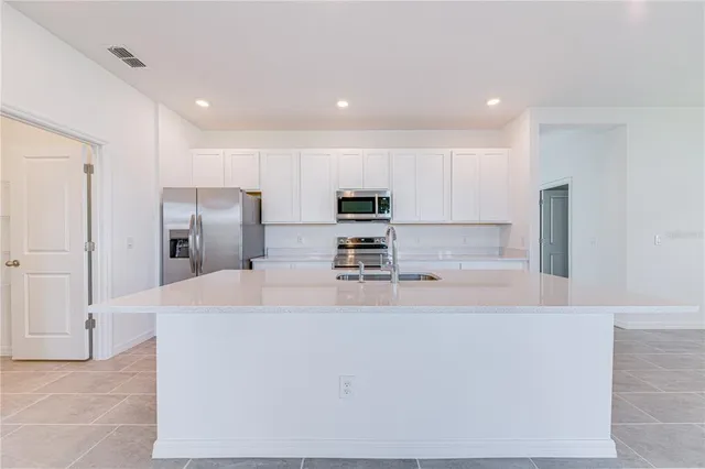 a large kitchen with stainless steel appliances a refrigerator and a stove top oven