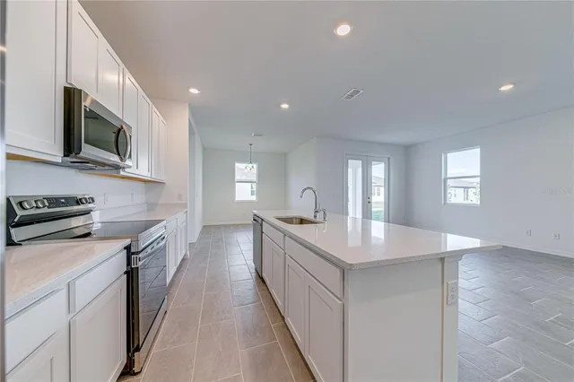 a large kitchen with stainless steel appliances granite countertop a lot of counter space and wooden floor