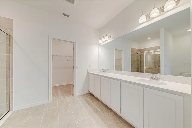 a large white bathroom with a double vanity sink and a mirror