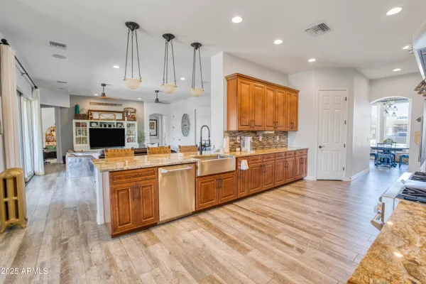 a large kitchen with stainless steel appliances kitchen island granite countertop a stove a sink dishwasher and a fireplace with wooden floor