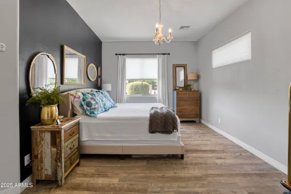 a bedroom with a bed a dresser and potted plants
