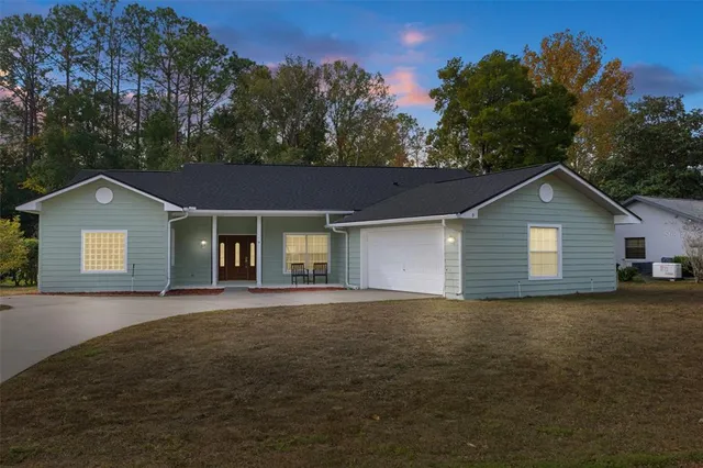 a front view of house with yard and trees in the background