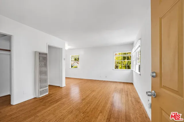 a view of an empty room with wooden floor and a window