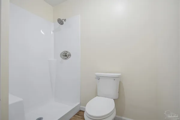 a white toilet sitting next to a shower