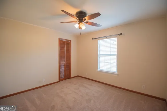 an empty room with a chandelier fan and closet area