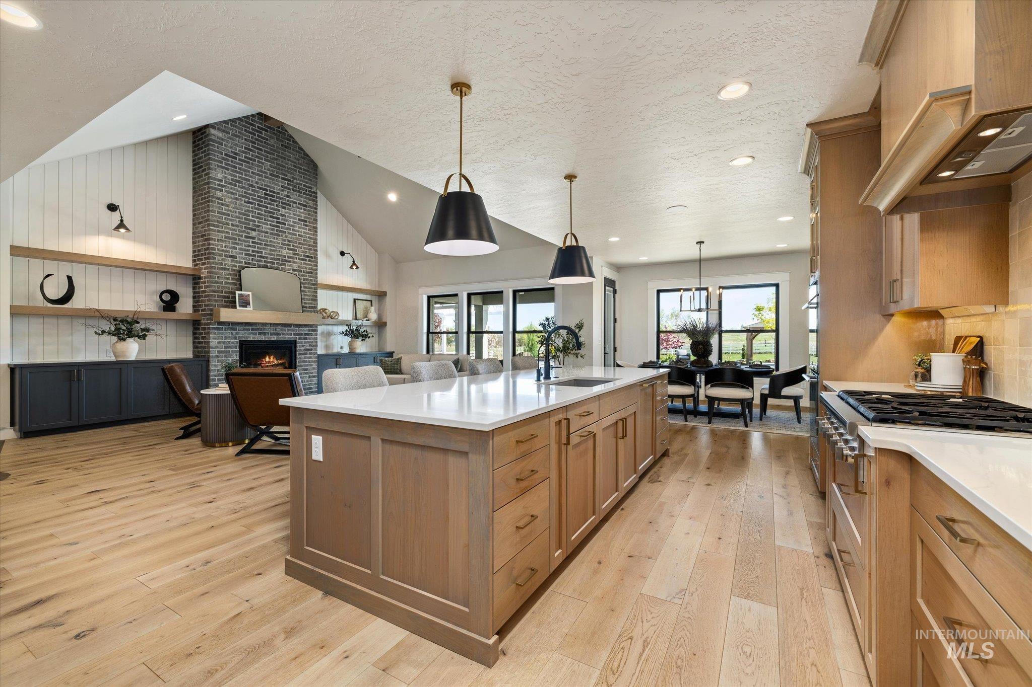 14857 Elk Spg Street Caldwell, ID 83607 - Photo 37 of 40 Kitchen featuring open floor plan, light wood-style floors, a spacious island, light stone countertops, and a high textured ceiling