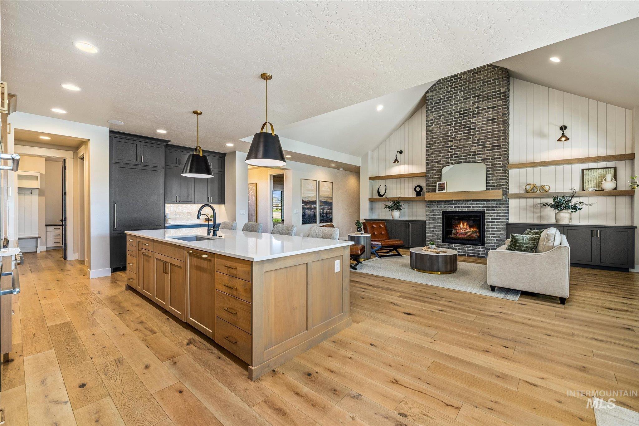 14857 Elk Spg Street Caldwell, ID 83607 - Photo 38 of 40 Kitchen with open floor plan, a large island, light wood finished floors, a fireplace, and dual tone cabinetry