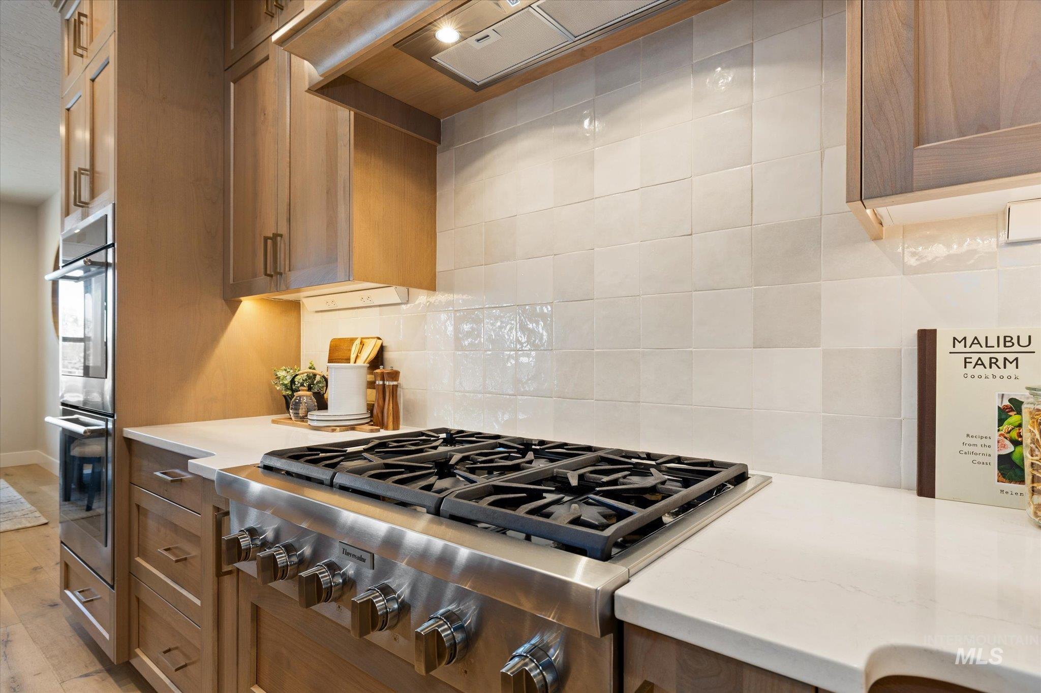 14857 Elk Spg Street Caldwell, ID 83607 - Photo 12 of 40 Kitchen with stainless steel appliances, light stone countertops, tasteful backsplash, and light wood-type flooring