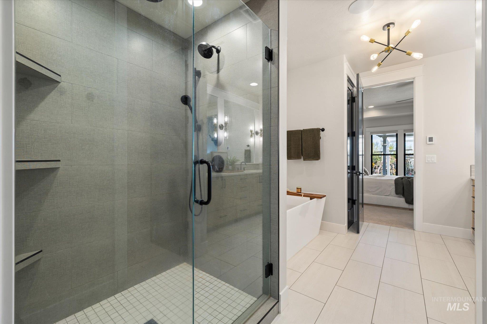 14857 Elk Spg Street Caldwell, ID 83607 - Photo 17 of 40 Full bathroom featuring connected bathroom, a freestanding bath, a stall shower, light tile patterned floors, and suspended lighting