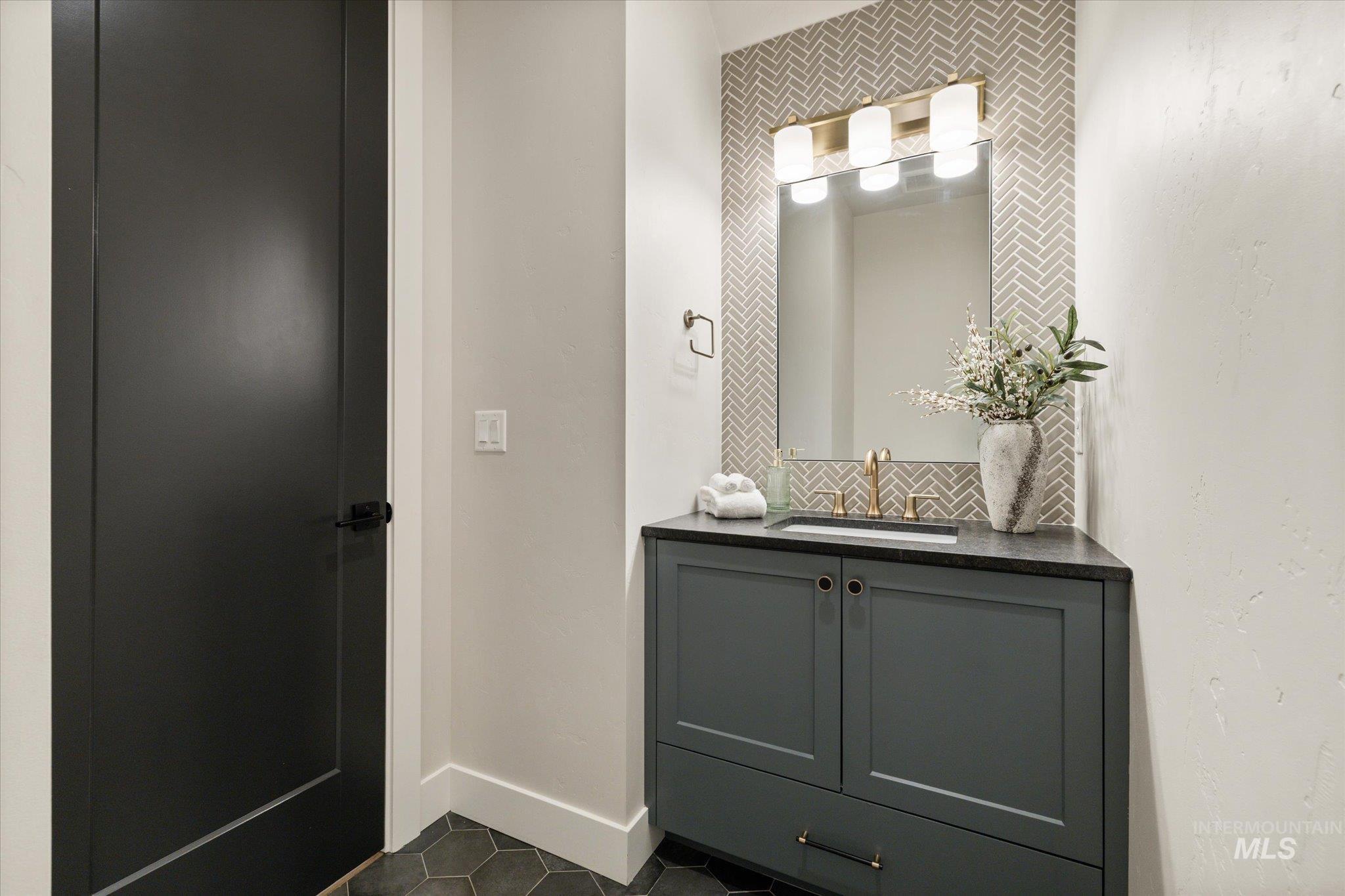 14857 Elk Spg Street Caldwell, ID 83607 - Photo 28 of 40 Half bathroom with decorative backsplash, vanity, and dark tile patterned floors