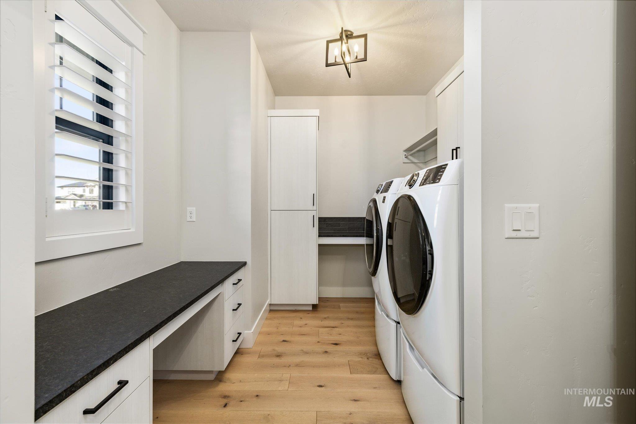 14857 Elk Spg Street Caldwell, ID 83607 - Photo 30 of 40 Laundry area featuring a desk, light wood-style floors, washing machine and clothes dryer, and cabinet space