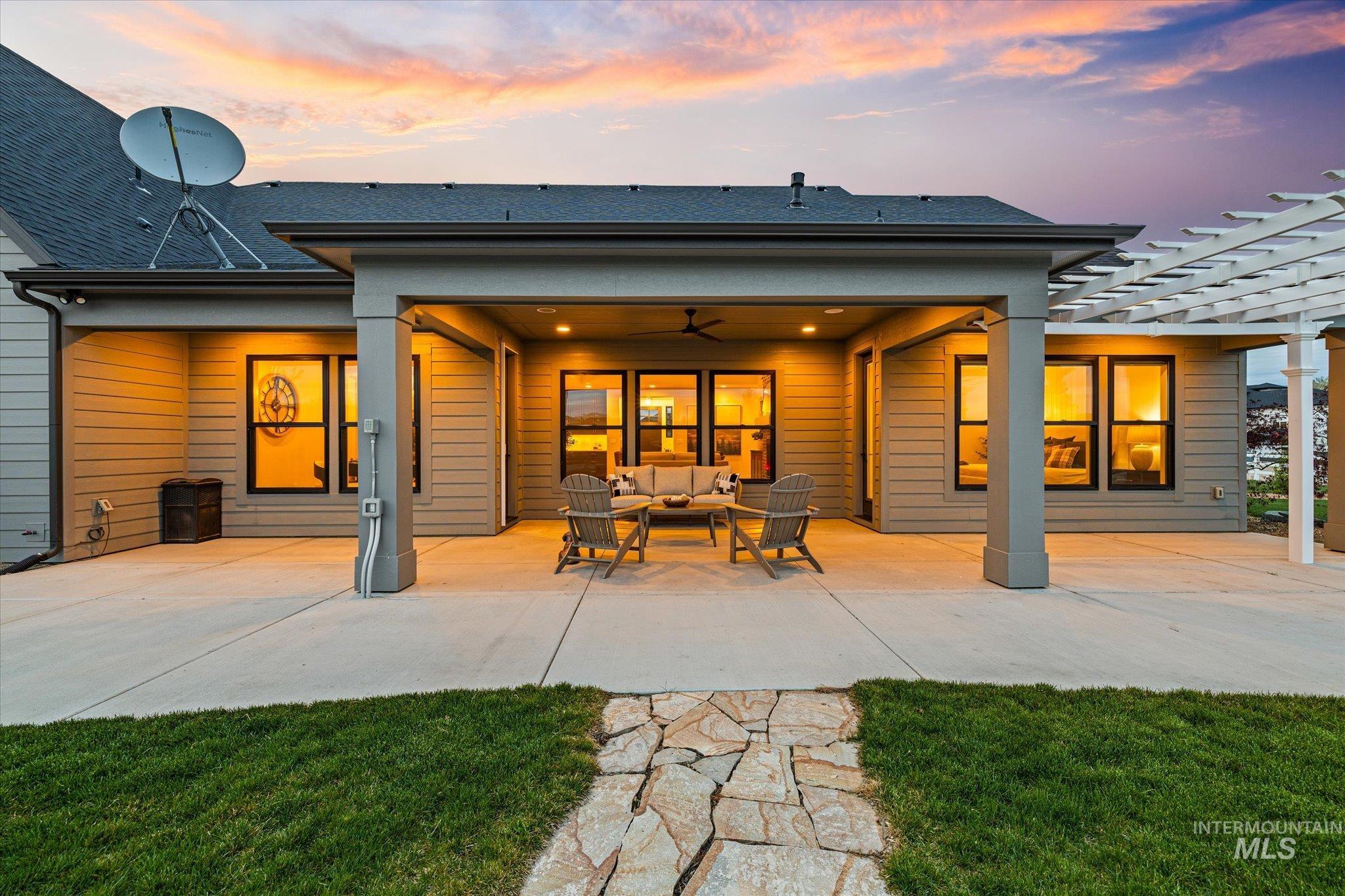 14857 Elk Spg Street Caldwell, ID 83607 - Photo 32 of 40 Back of house at dusk with a patio area, a ceiling fan, outdoor seating, a pergola, and a lawn