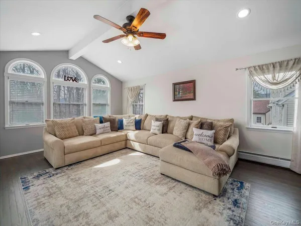 a living room with furniture a large window and a ceiling fan
