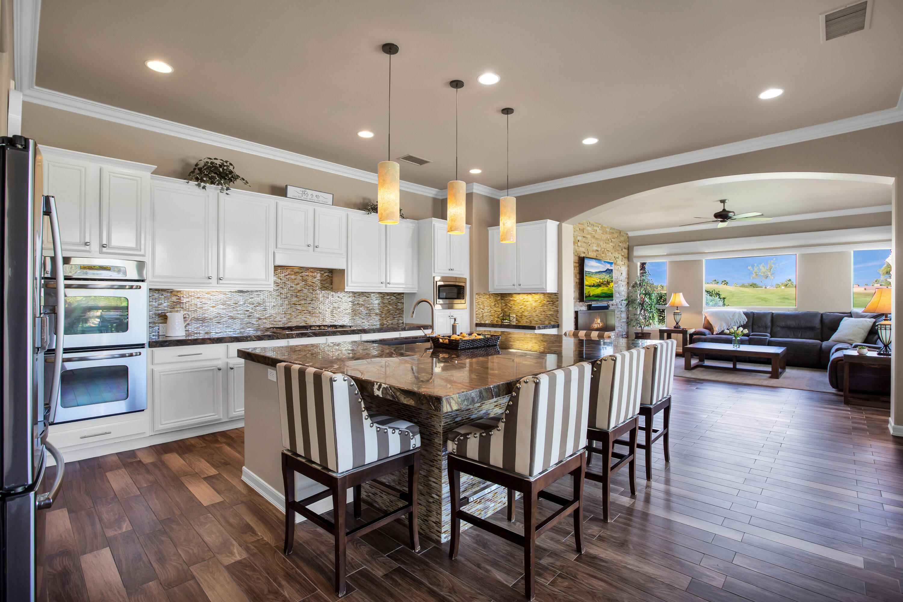 390 Loch Lomond Road Rancho Mirage, CA 92270 - Photo 16 of 55 a kitchen with stainless steel appliances granite countertop a stove top oven a refrigerator a sink and white cabinets with wooden floor