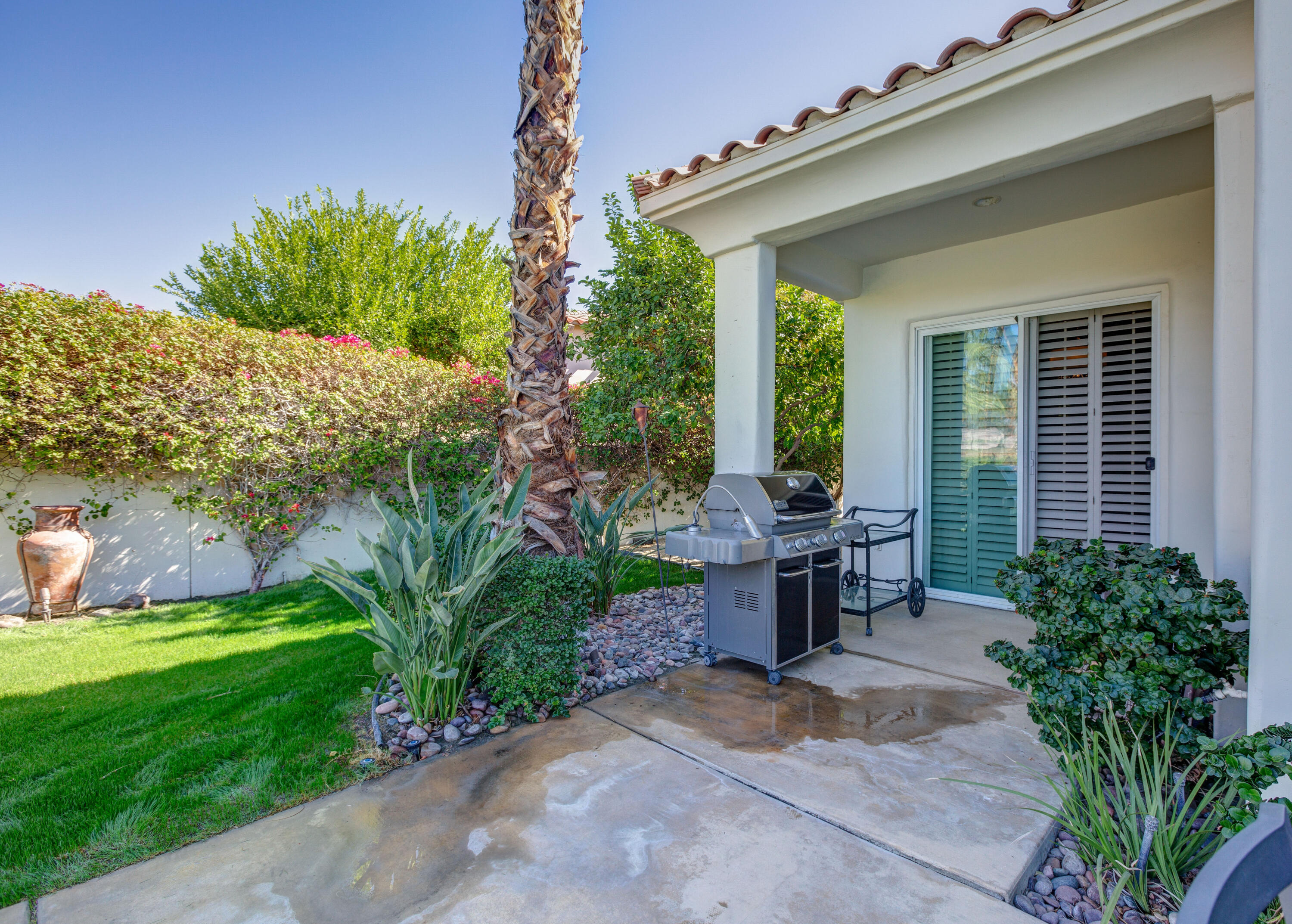 390 Loch Lomond Road Rancho Mirage, CA 92270 - Photo 48 of 55 a view of a patio with table and chairs potted plants and floor to ceiling window