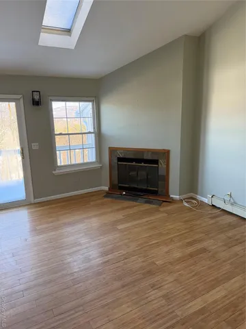 a view of empty room with wooden floor and fireplace