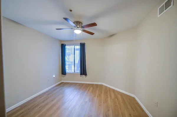 a view of an empty room with window and wooden floor