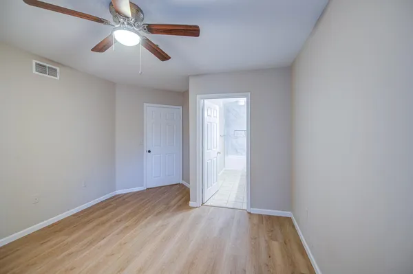 a view of an empty room and window and chandelier fan