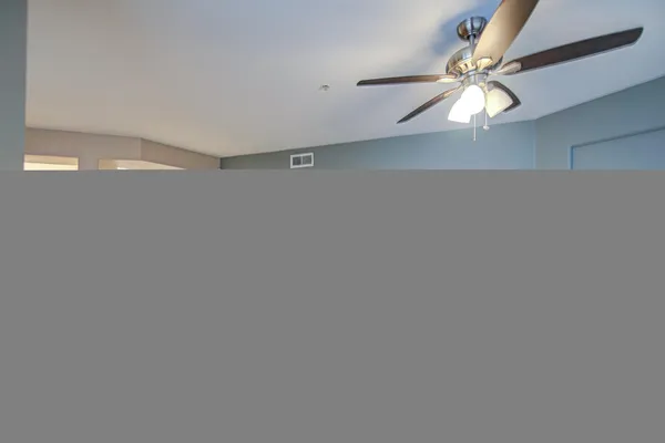 a view of a room with a ceiling fan and wooden floor