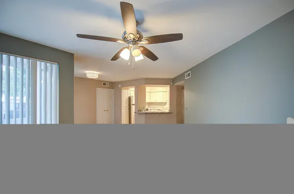 a view of a big room with windows and chandelier fan