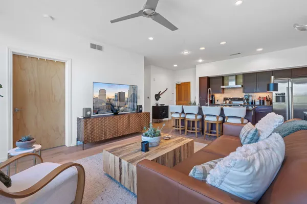 a living room with furniture kitchen view and a wooden floor