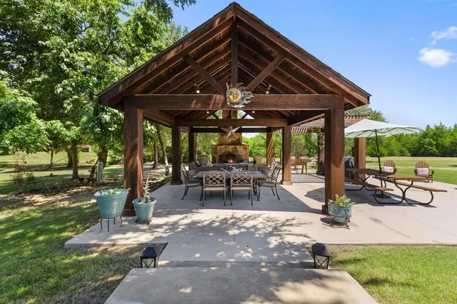 a view of patio with table and chairs under an umbrella with a barbeque