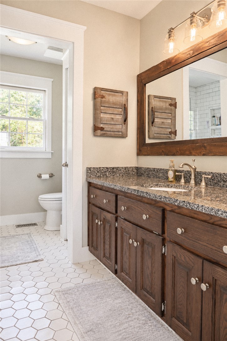 2420 Rainey Road Starr, SC 29684 - Photo 16 of 36 Rich wood cabinets and granite countertops elevate this master bathroom with a timeless aesthetic.