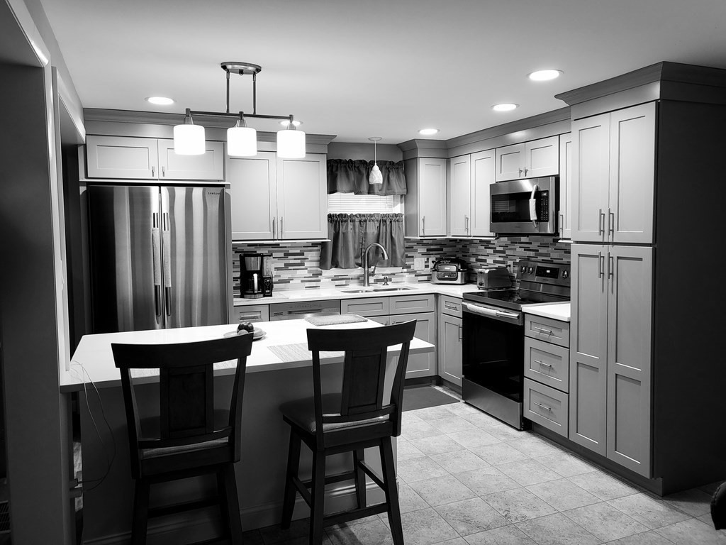 246 Lamont Street Springfield, MA 01119 - Photo 6 of 23 a kitchen with stainless steel appliances a dining table chairs refrigerator and microwave
