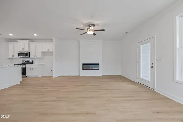 a view of an empty room with a window and wooden floor