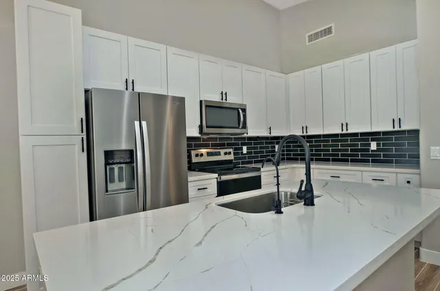 a kitchen with kitchen island granite countertop a sink cabinets and stainless steel appliances