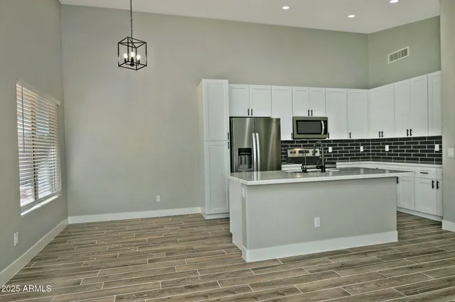 a kitchen with stainless steel appliances a refrigerator a sink a stove and white cabinets