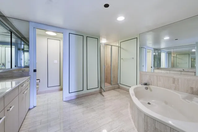 a spacious bathroom with a granite countertop tub sink shower and mirror