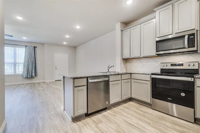 a kitchen with stainless steel appliances granite countertop a stove a sink and a microwave