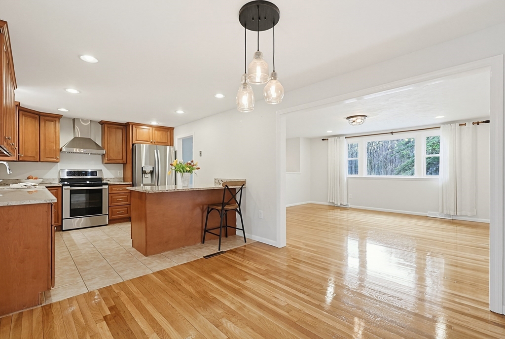26 Beaver Brook Road Sharon, MA 02067 - Photo 14 of 42 a kitchen with stainless steel appliances granite countertop a refrigerator a sink dishwasher a stove and a dining table with wooden floor