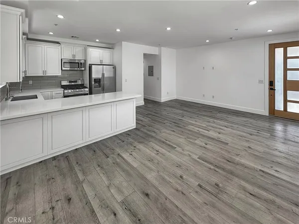 a large kitchen with stainless steel appliances granite countertop a large counter top and a stove with wooden floor