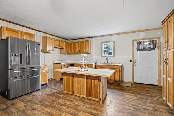 a kitchen with stainless steel appliances granite countertop a refrigerator a sink dishwasher a stove with wooden cabinets and wooden floor