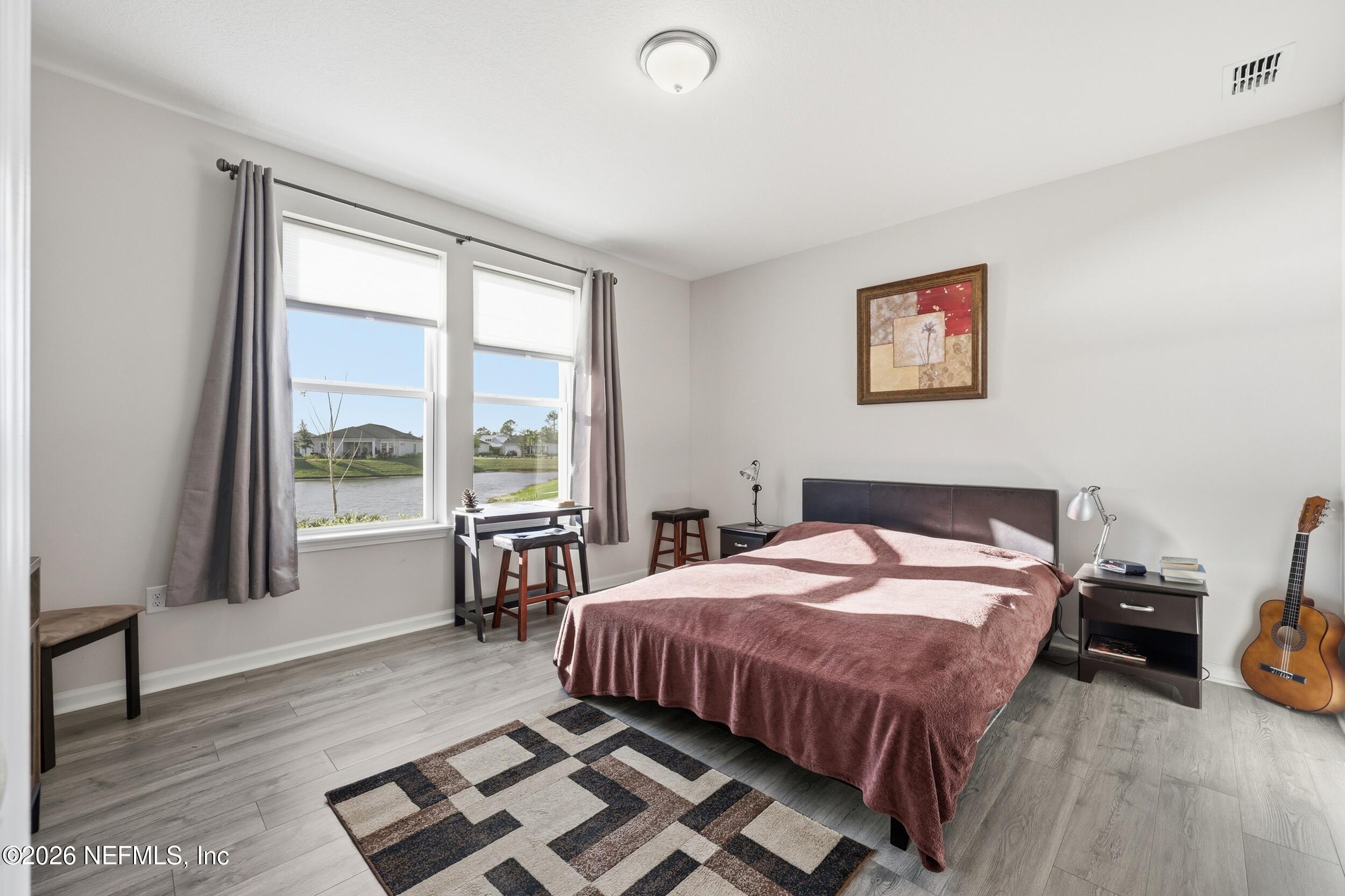 996 Rustic Mill Drive St. Augustine, FL 32092 - Photo 20 of 53 a bedroom with a bed next to a large window with wooden floor