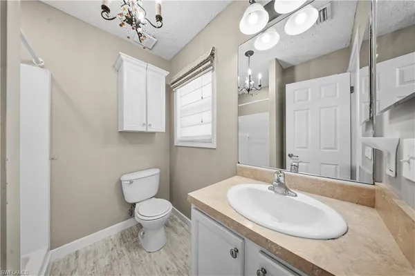 a bathroom with a toilet a sink a mirror a window and vanity