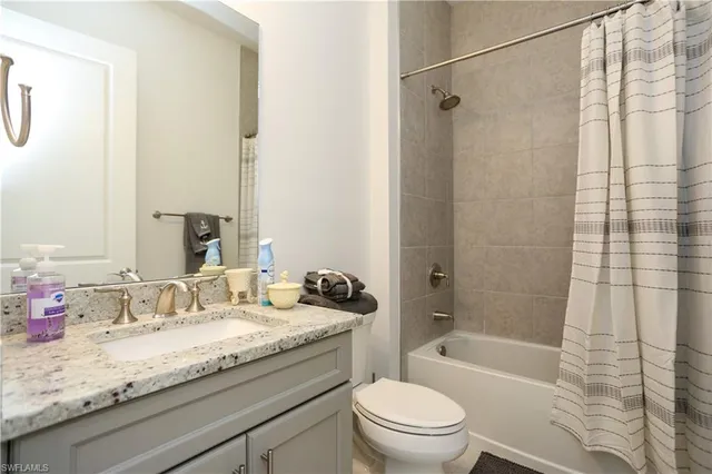 a bathroom with a granite countertop sink a toilet a mirror a bathtub and shower