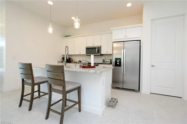 a kitchen with stainless steel appliances a refrigerator a stove a sink a table and chairs