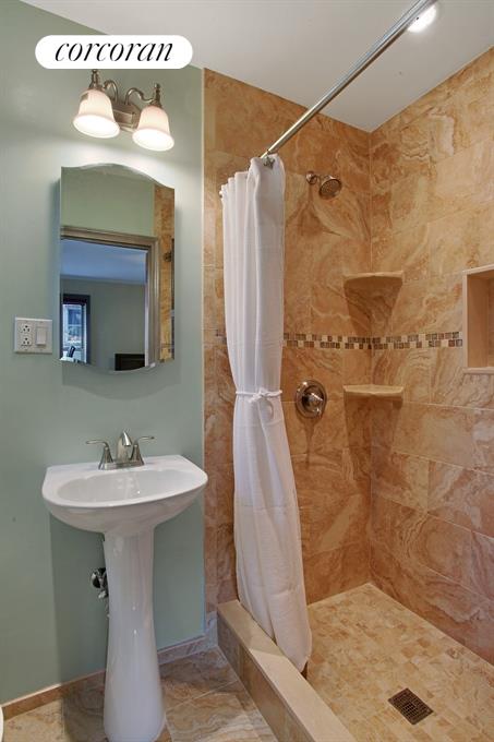 9281 Shore Road, Unit 207 Brooklyn, NY 11209 - Photo 1 of 1 a bathroom with a sink a mirror and shower