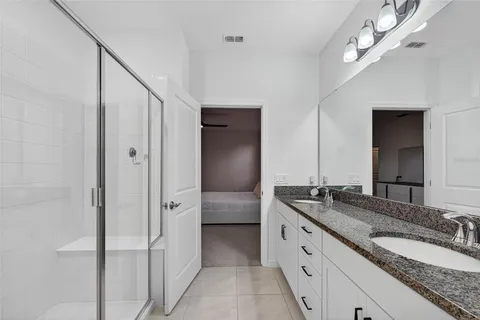 a spacious bathroom with a granite countertop double vanity sink a mirror and a shower
