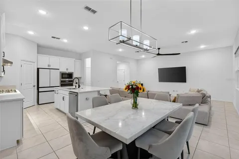 a living room with stainless steel appliances furniture a flat screen tv and kitchen view