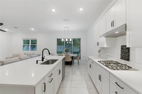a kitchen with sink a stove and white cabinets