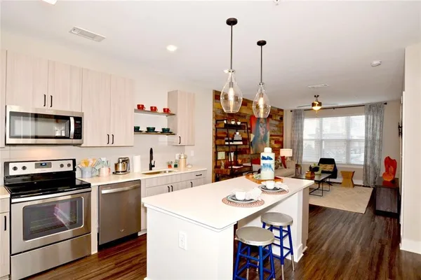 a open kitchen with stainless steel appliances kitchen island granite countertop a stove a sink a dining table and chairs with wooden floor