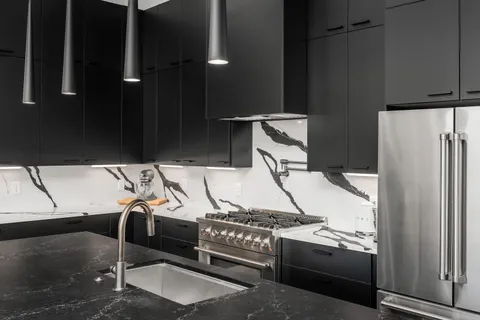 a view of a kitchen with stainless steel appliances kitchen island granite countertop a refrigerator and a stove