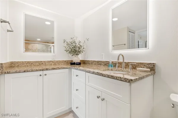a bathroom with a granite countertop sink and a mirror